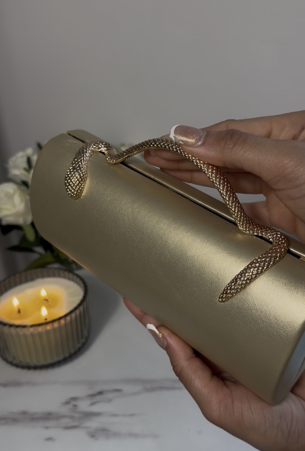 Golden Snake Clutch with a textured metallic finish and sculptural snake handle