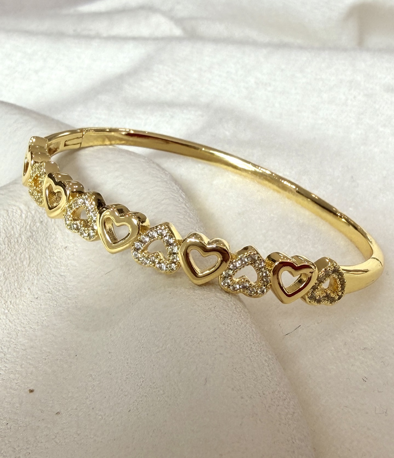 Gold-tone bangle with alternating open gold and crystal hearts