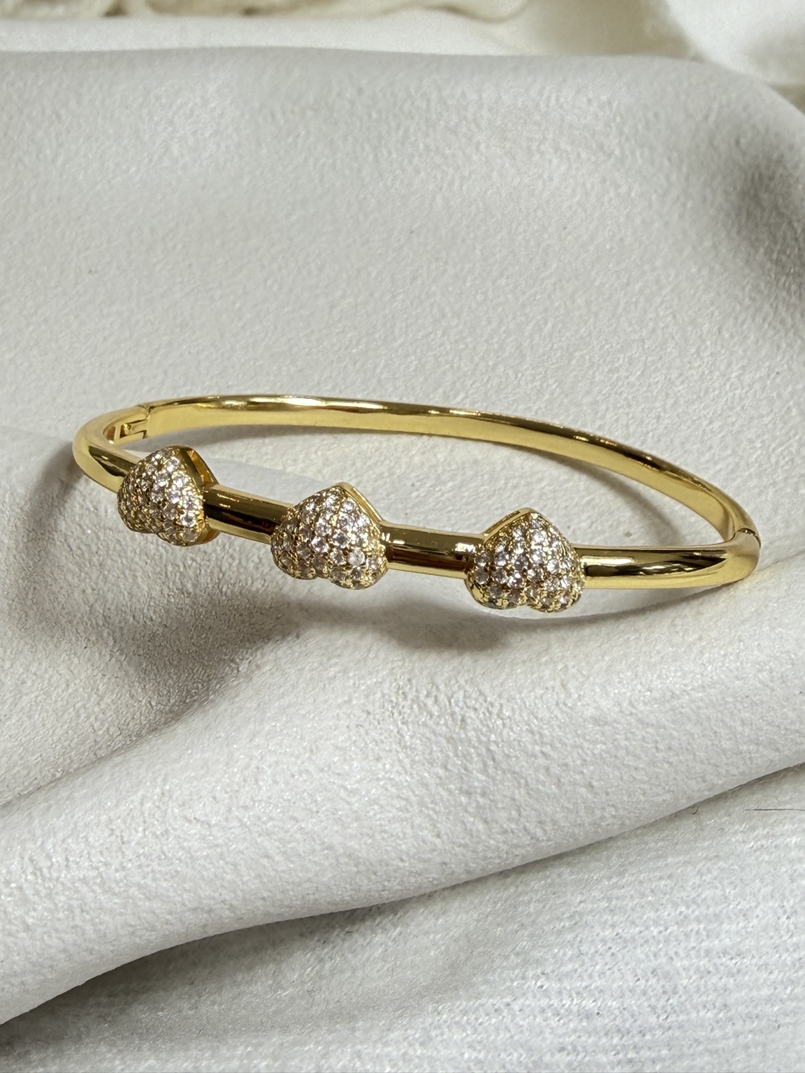 Gold-tone bangle with three pavé crystal hearts